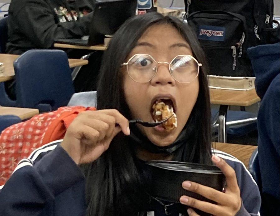 Freshman Jayden Kay Linayao feasts on the cafeterias delicious orange chicken.
